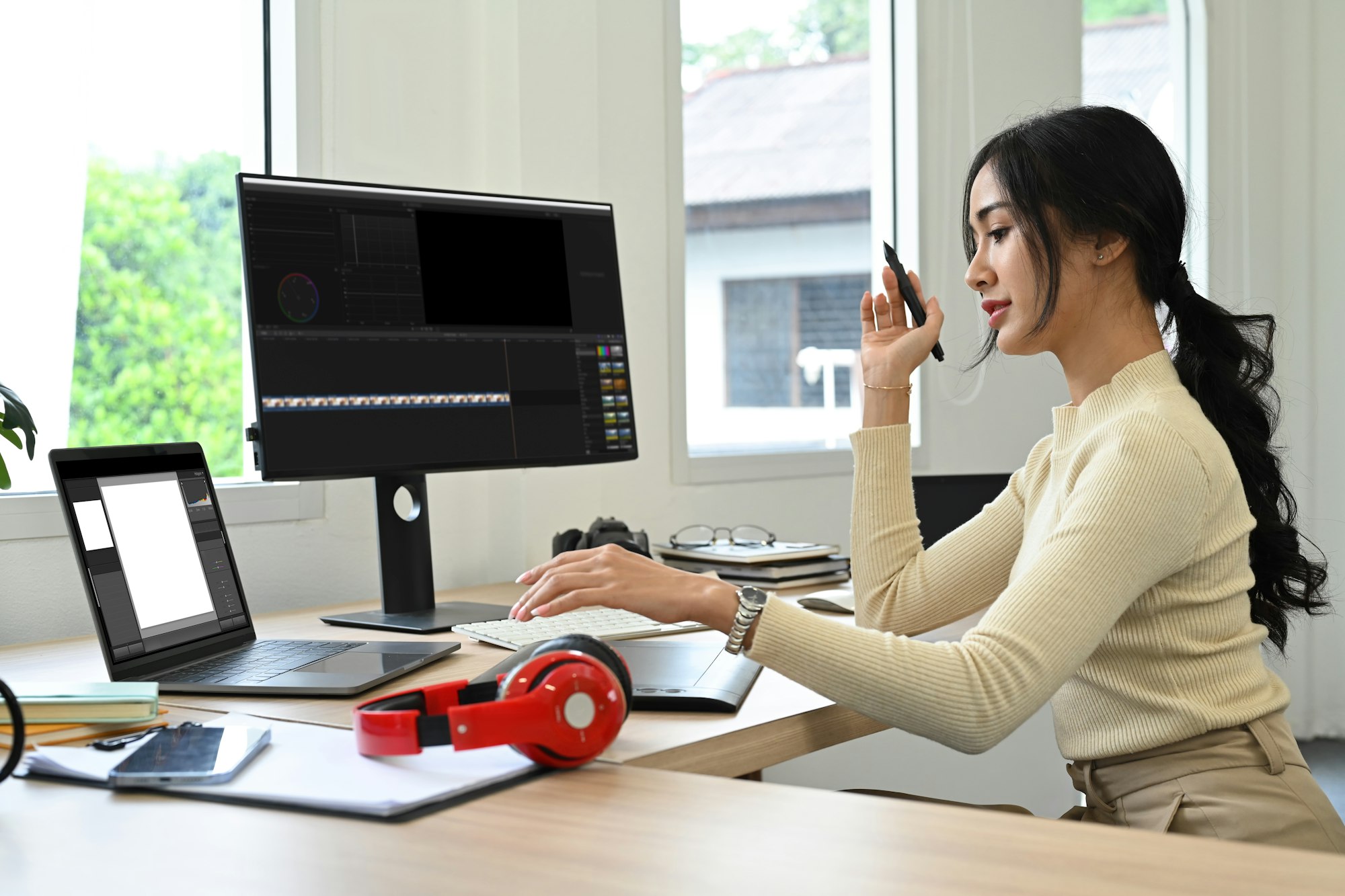Young female content creator editing video footage with professional computer at her workstation.